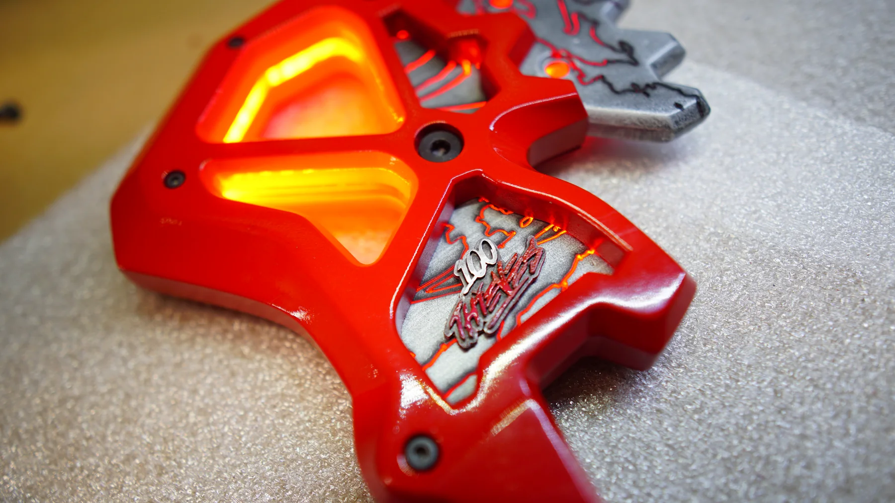 The NiceWigg Gibraltar Heirloom axe by Hoku Props, red frame and resin blade, fitted into its foam-lined carry case with a 100 Thieves plate