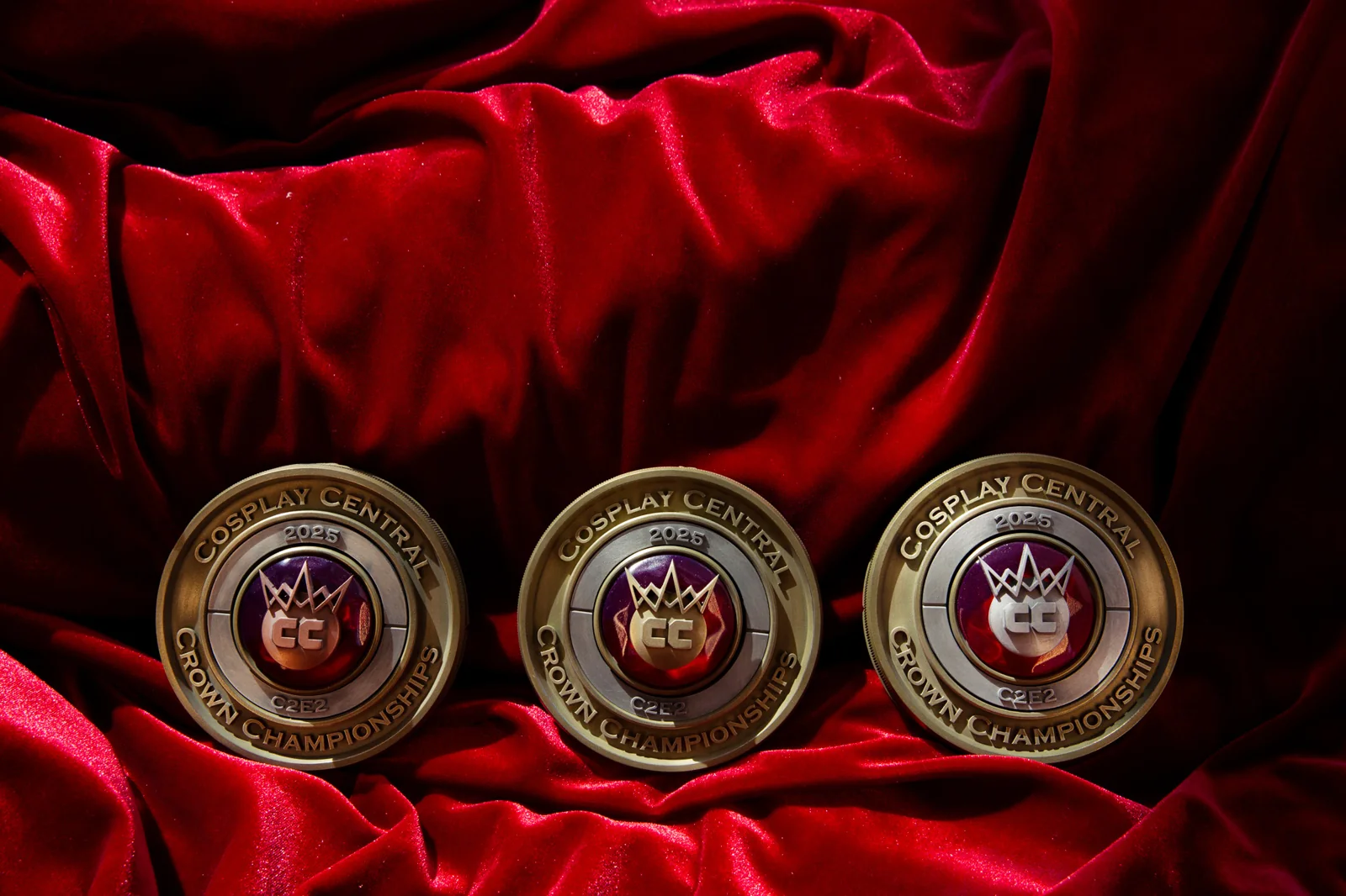 Three 2025 C2E2 Crown Championships placement medals by Hoku Props in a row on red velvet