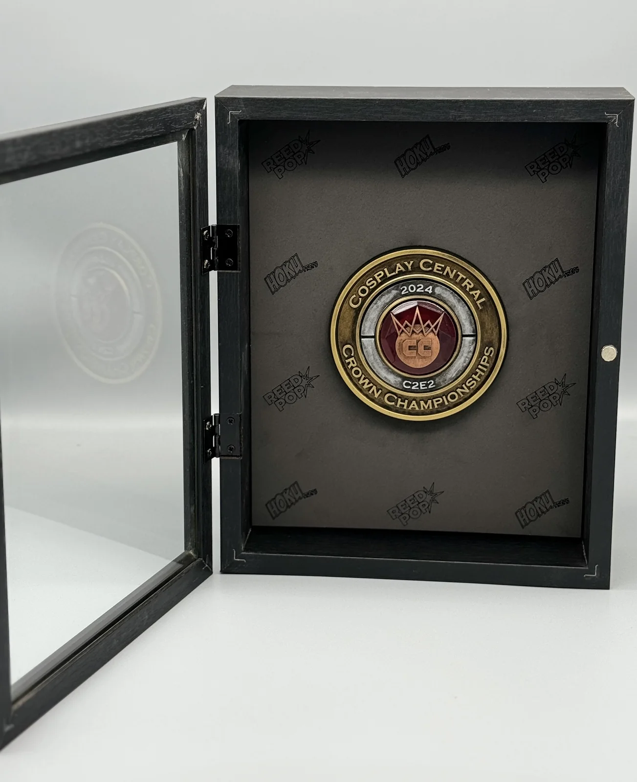 A 2024 C2E2 Crown Championships medal by Hoku Props mounted in its black presentation box with the glass door open