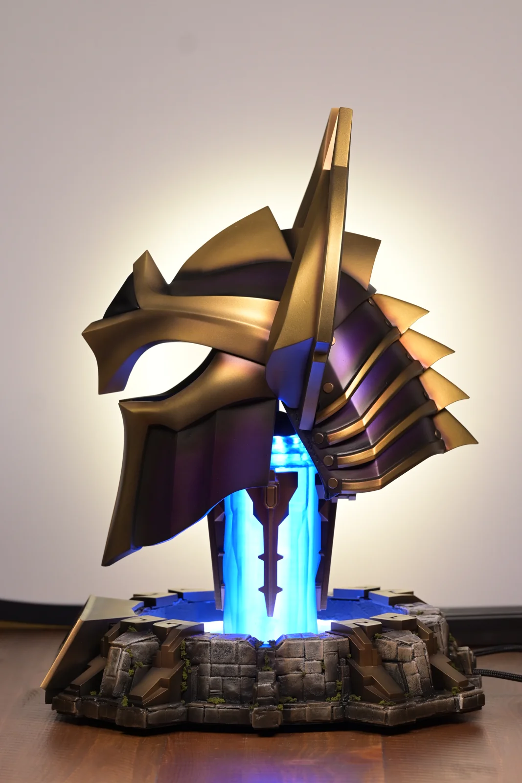The Champions Queue 2023 trophy by Hoku Props from a three-quarter angle, the helmet floating over its lit blue column