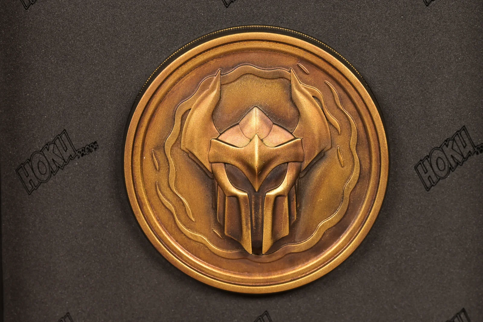 Close-up of a cast bronze Champions Queue medallion by Hoku Props with a raised helmet emblem