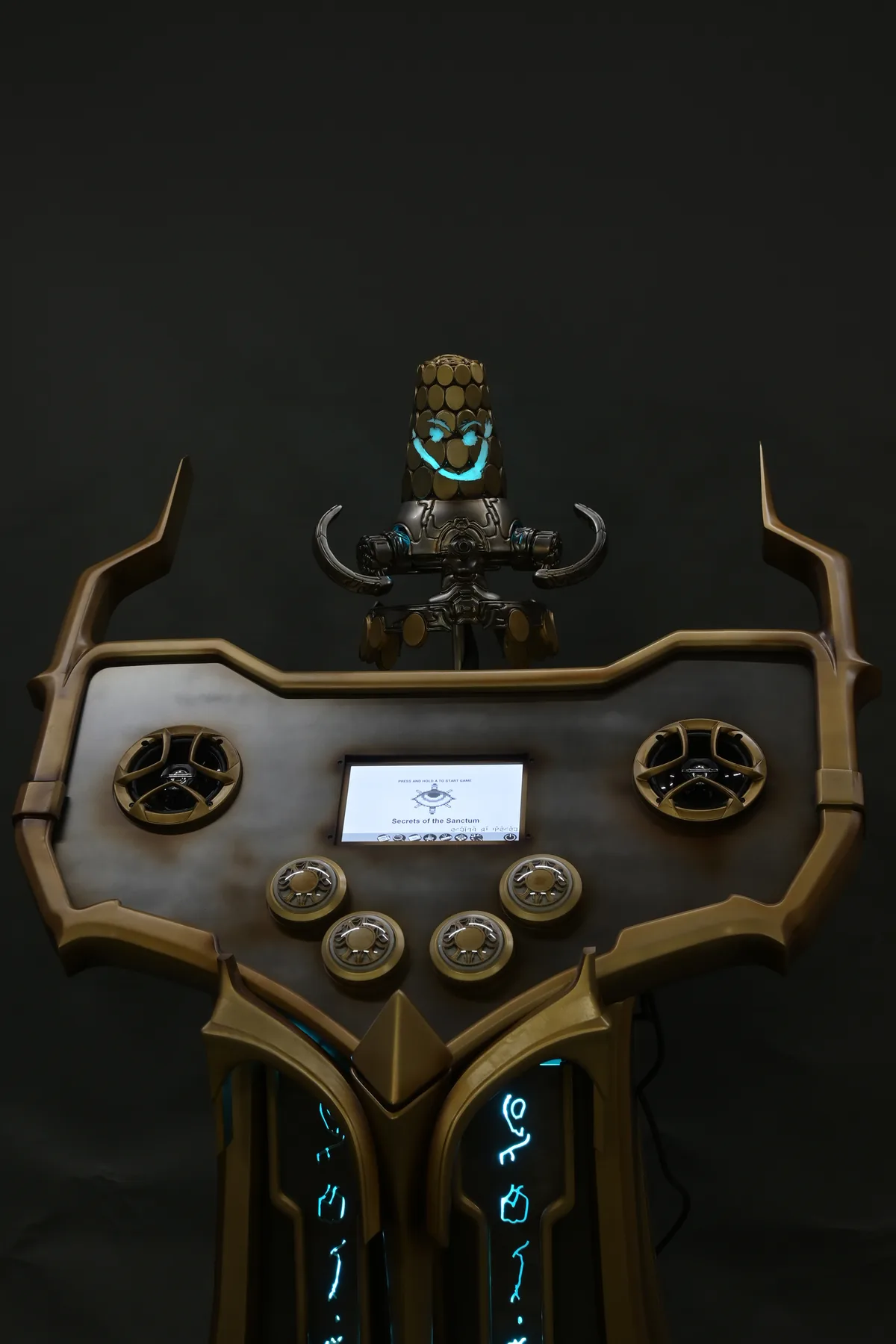 Closer view of the gold framed control panel and lit glyphs on the Secrets of the Sanctum cabinet