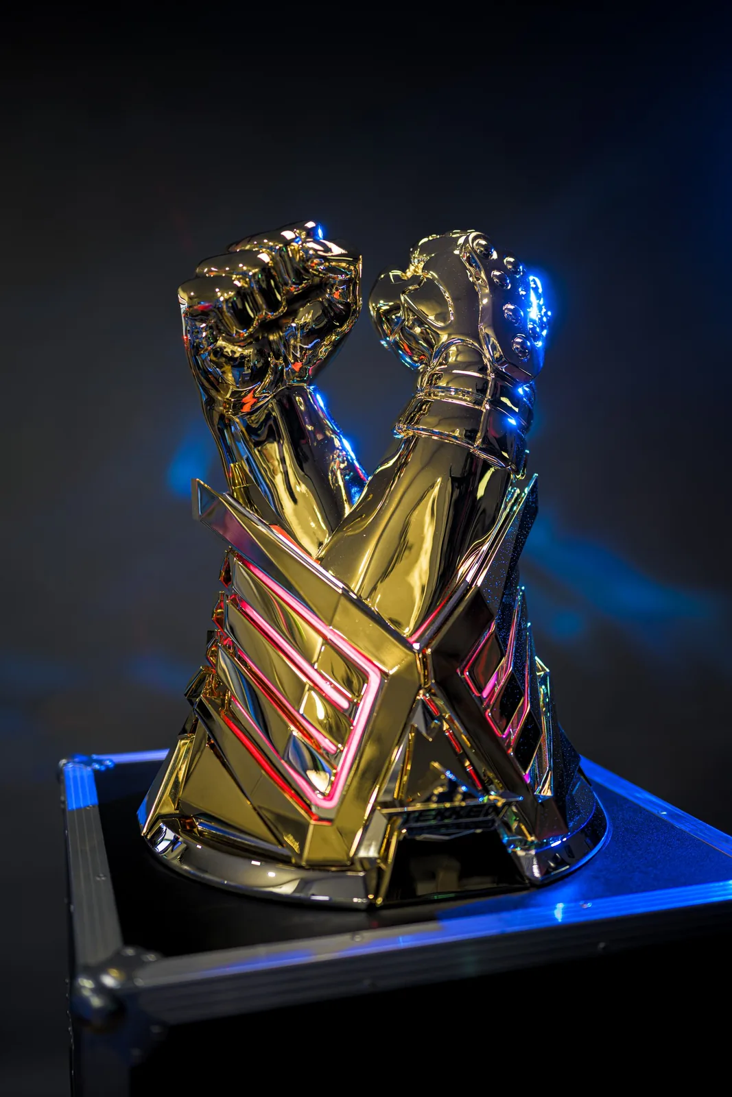 The finished gold TEKKEN World Tour 2025 trophy lit blue on top of its black road case