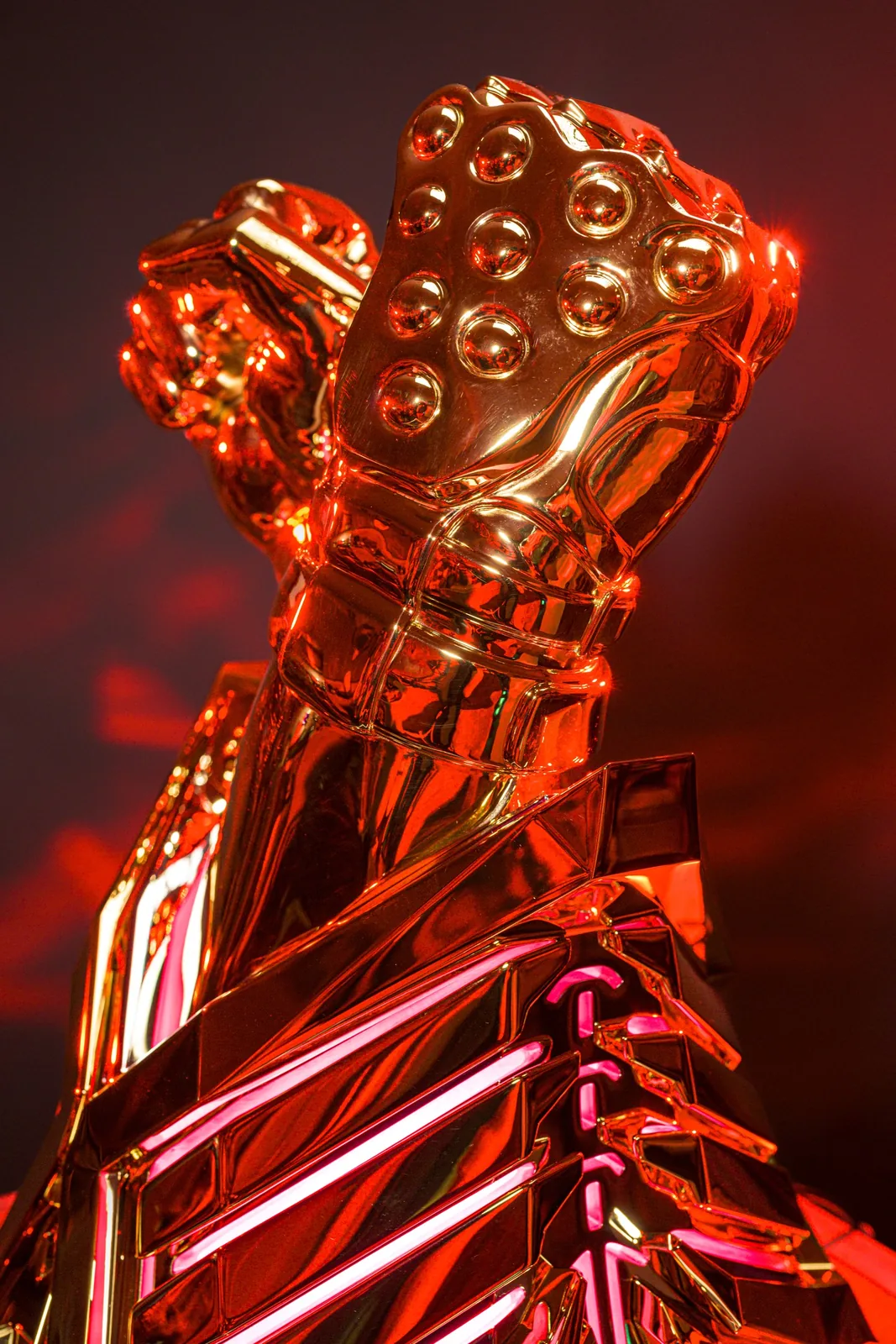 The studded gold fist of the TEKKEN World Tour 2025 trophy catching red light