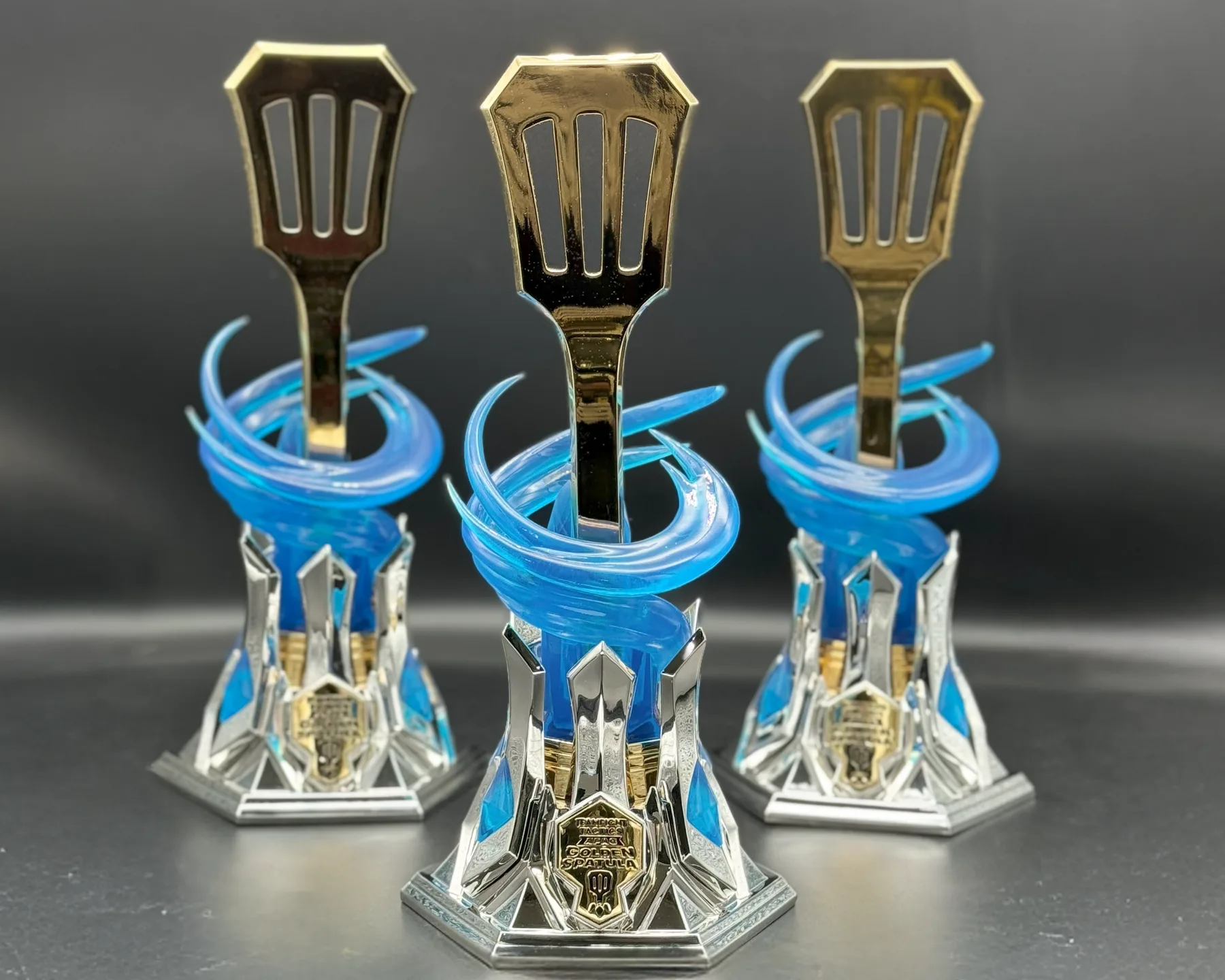 A Teamfight Tactics Golden Spatula trophy built by Hoku Props: a mirror-gold spatula rising through a translucent blue vortex on a chromed hextech base
