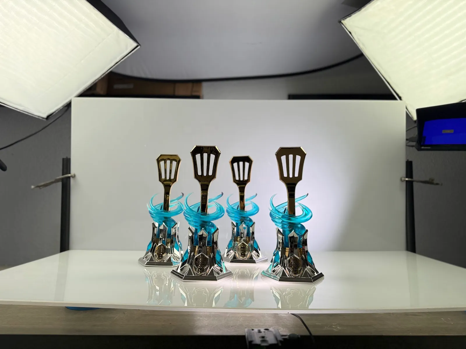 The finished Golden Spatula trophies lit on a white sweep in the Hoku Props studio lightbox