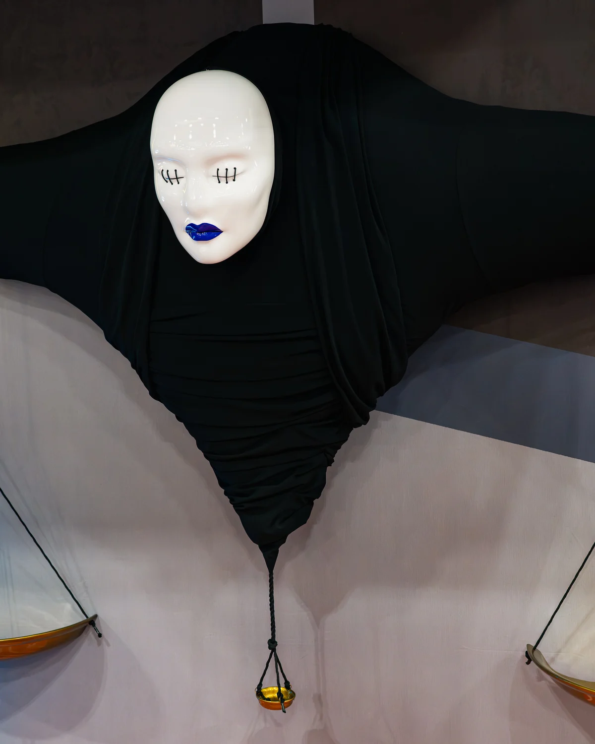 The Judgeman figure built by Hoku Props installed at the Jujutsu Kaisen: The Culling Game booth, a cast gloss-white face above a spread black robe with two hanging brass scales