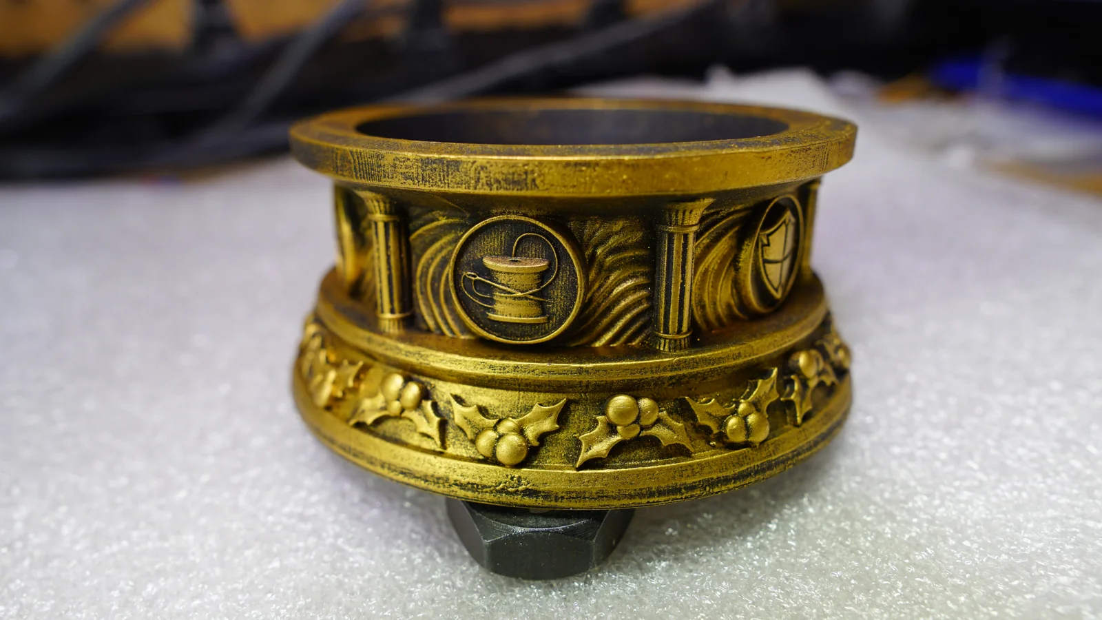 The gilded trophy base by Hoku Props with sculpted holly, columns and crest medallions