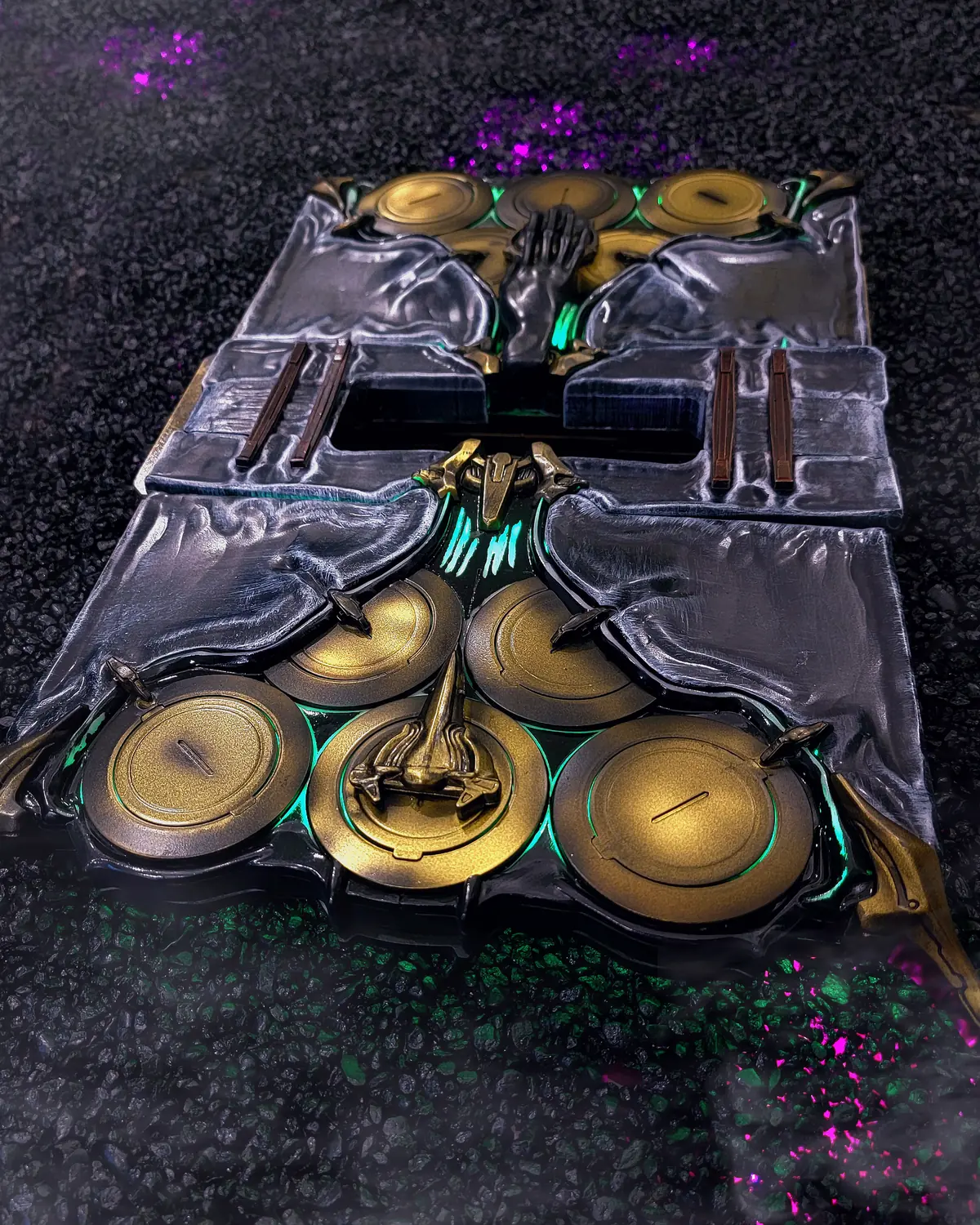 Albrecht's Grimoire prop by Hoku Props, a closed metal tome with a black skull, gold discs and teal internal glow