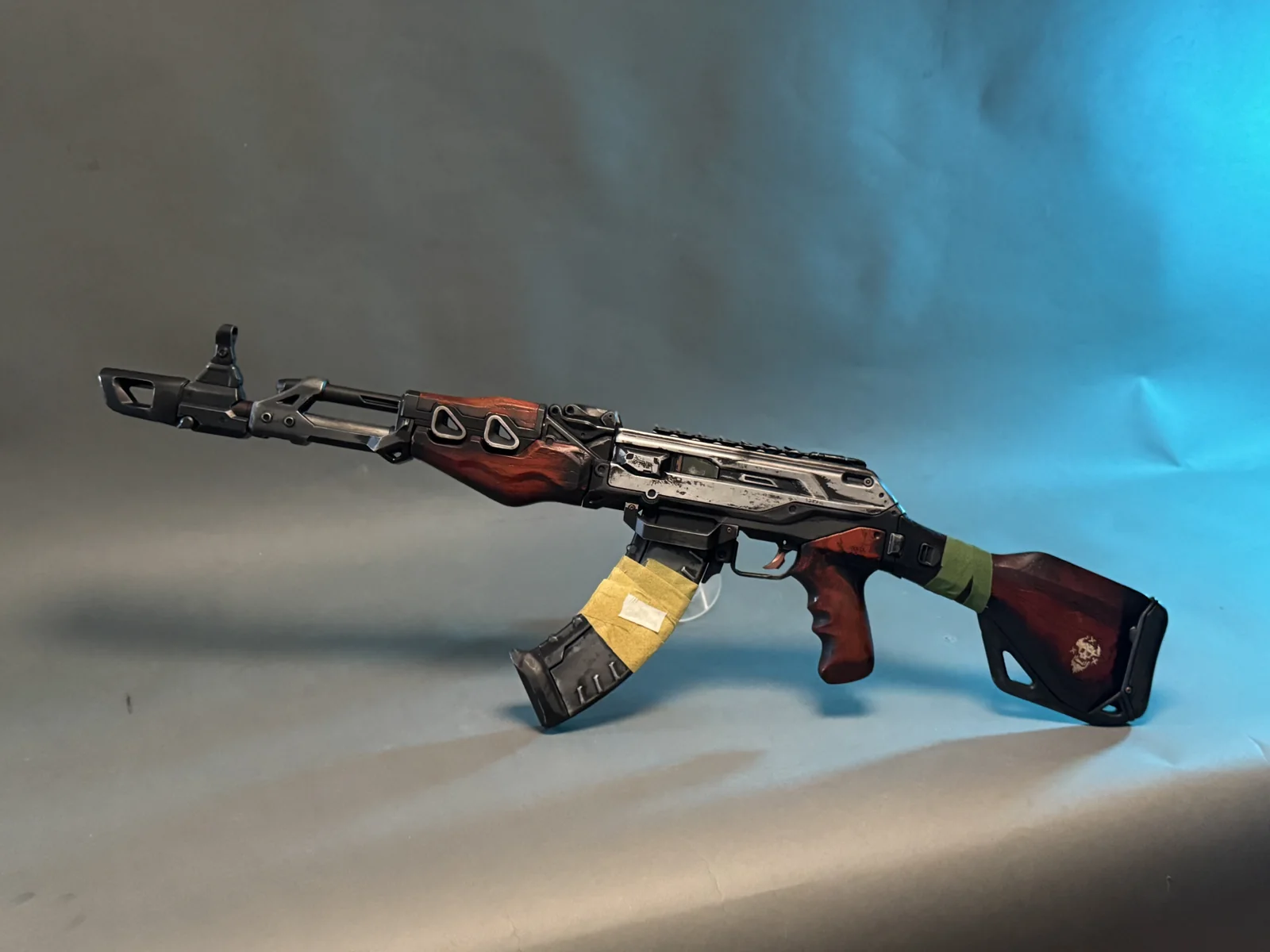 Highguard Dynasty rifle replica by Hoku Props with a red wood-grain stock and worn metal body, on a teal studio backdrop