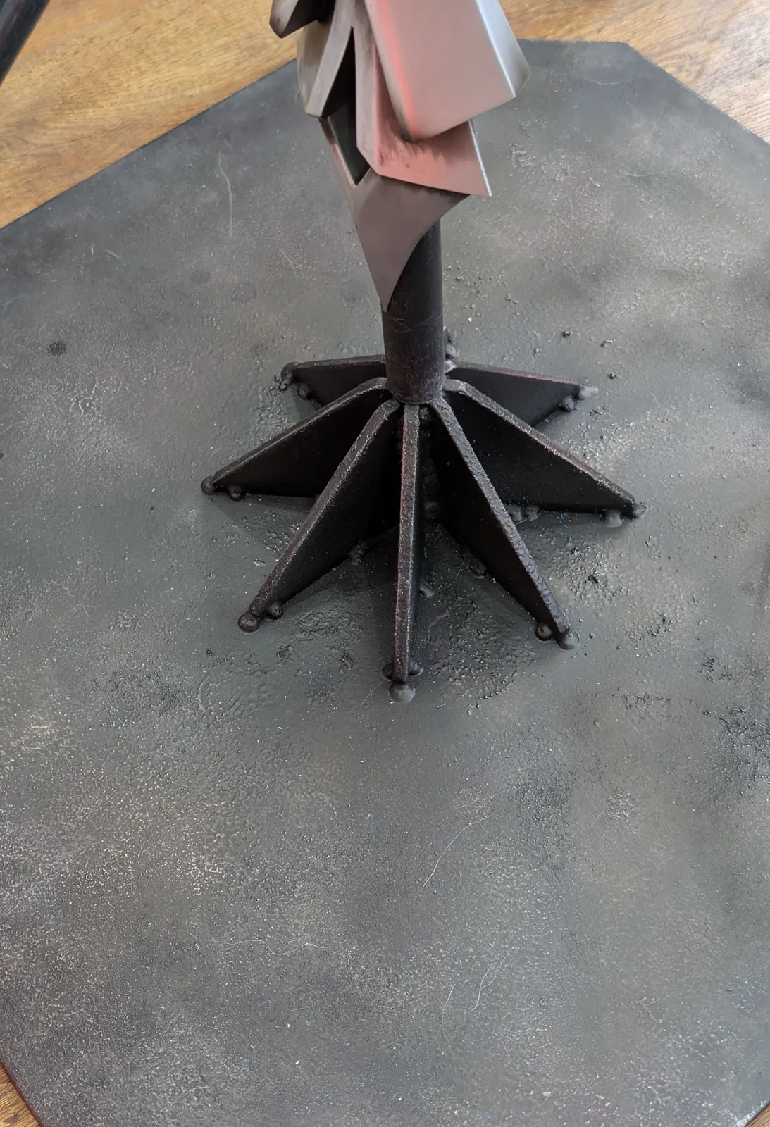 The custom welded base with radiating fins holding the foot of the spear upright