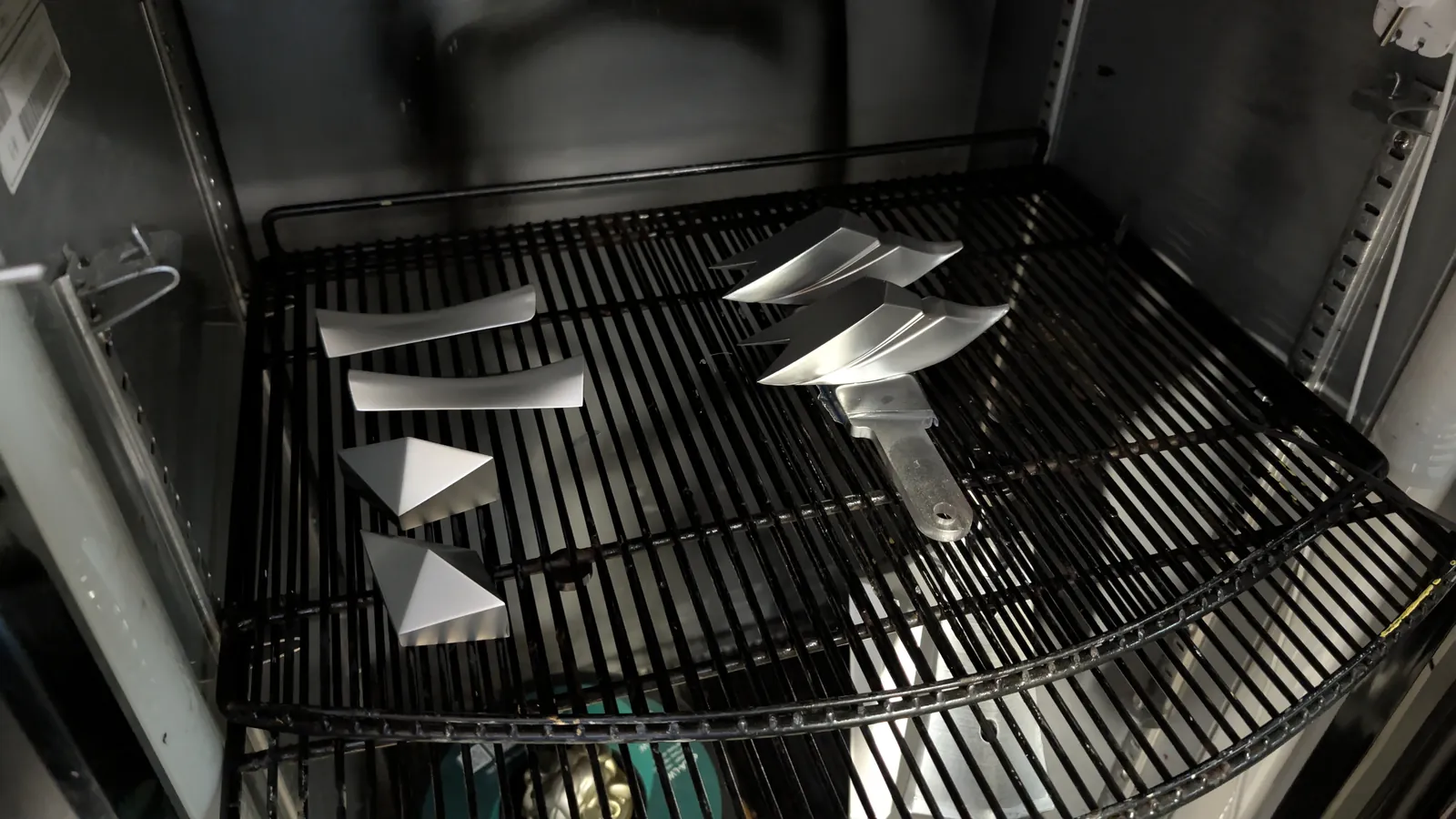 Freshly painted silver sections of the spear laid out on a drying rack