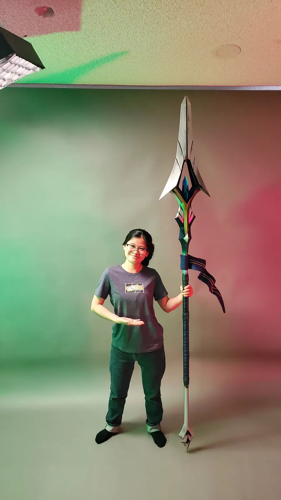 A Hoku Props team member standing beside the finished spear for scale